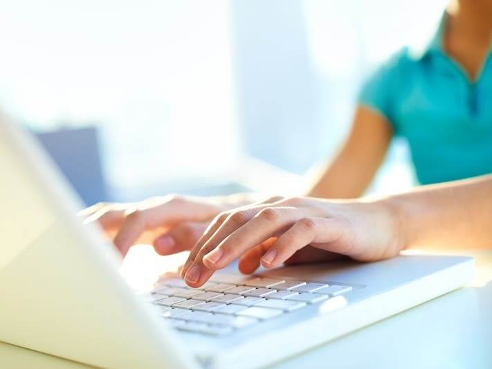 There is a pair of hands typing on a laptop keyboard