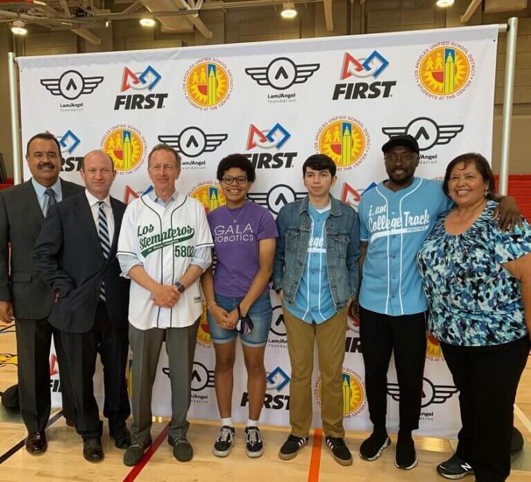 There is a group of people including Willi.am and GALA student Annika. They are in front of an event banner with other supporters of robotics and stem education.