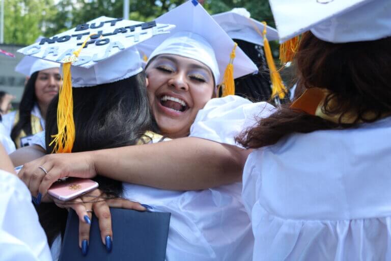 A TYWLS graduate smiles and hugs a fellow graduate.