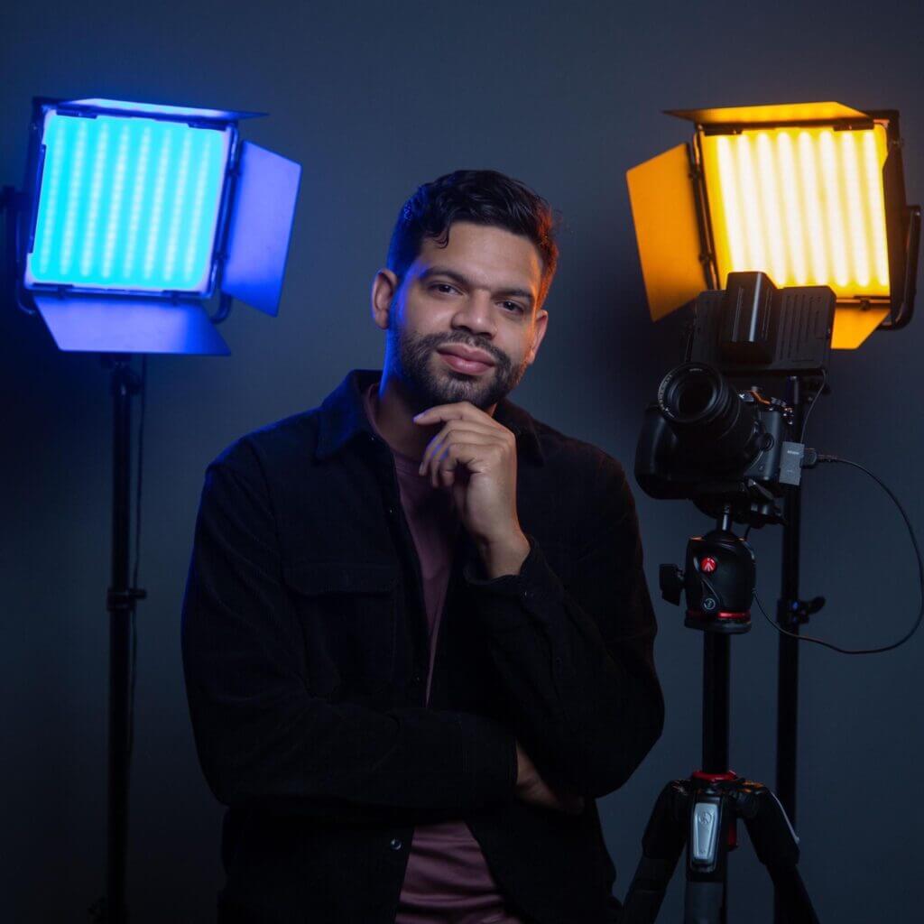 Phellix is sitting in between various professional lighting and video equipment.