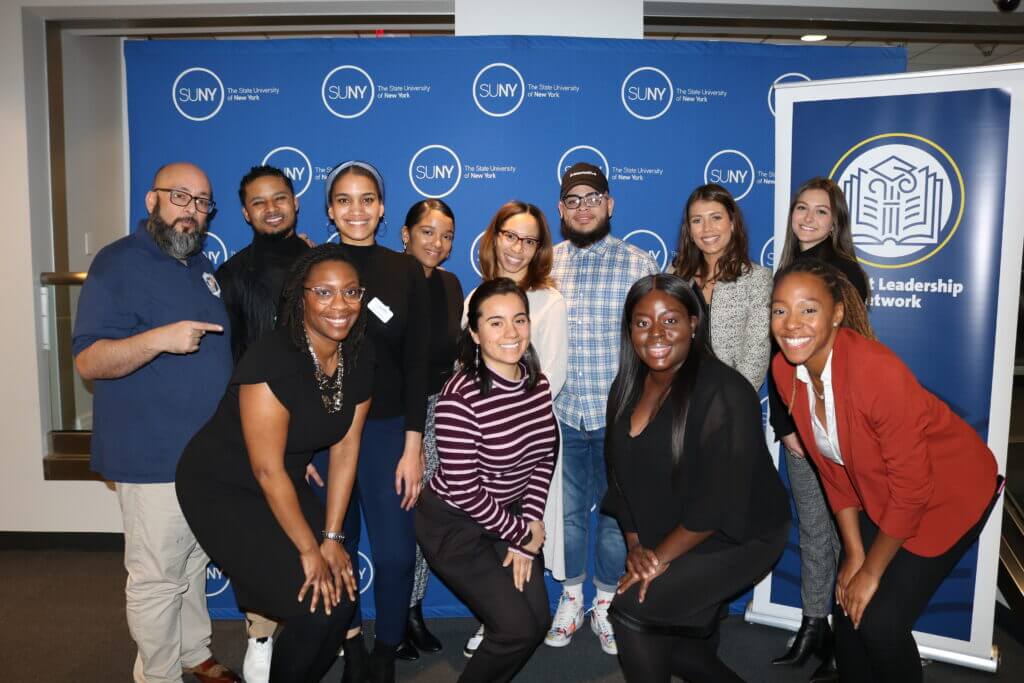 The Alumni Engagement team and FSS presenters pose for a group picture in front of a SUNY step and repeat banner. 
