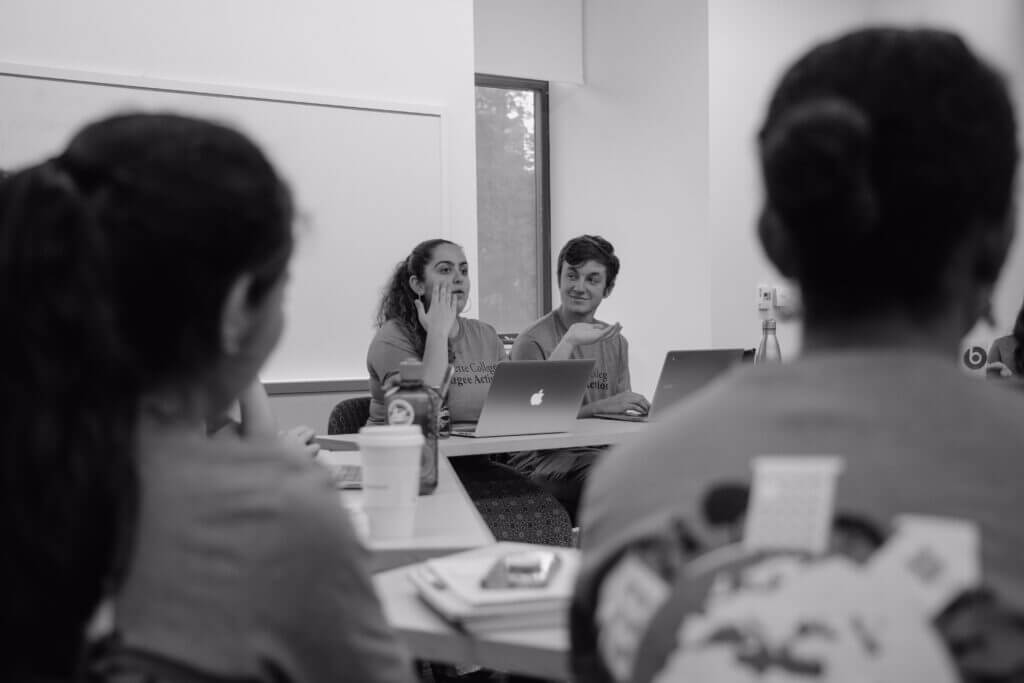 Ayat speaks passionately at a meeting and her peer listens attentively. 