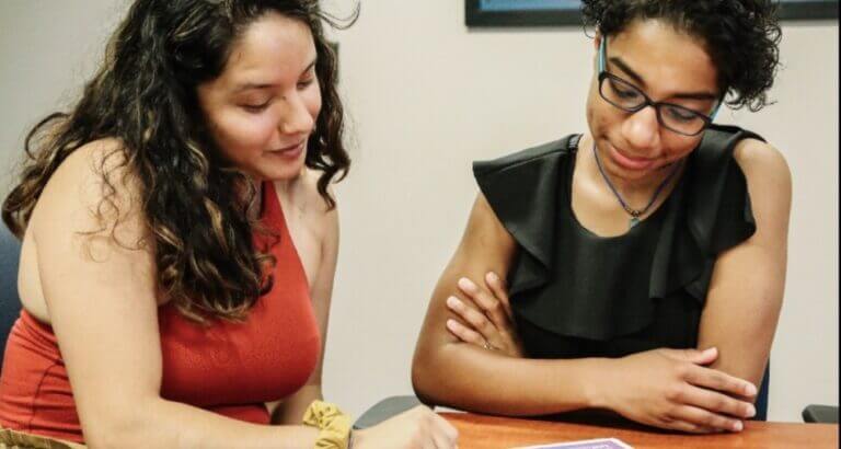 Photo courtesy of UP Partnership. There are two women sitting at a table and they are looking at a plan together.