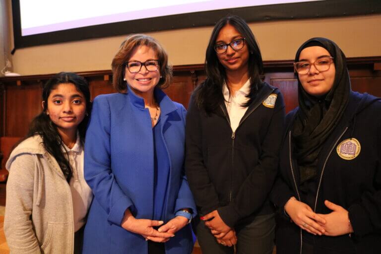 Valerie Jarrett stands in the center of three TYWLS students.