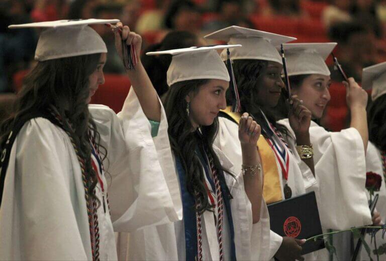 Graduates turn the tassel on their graduation caps.