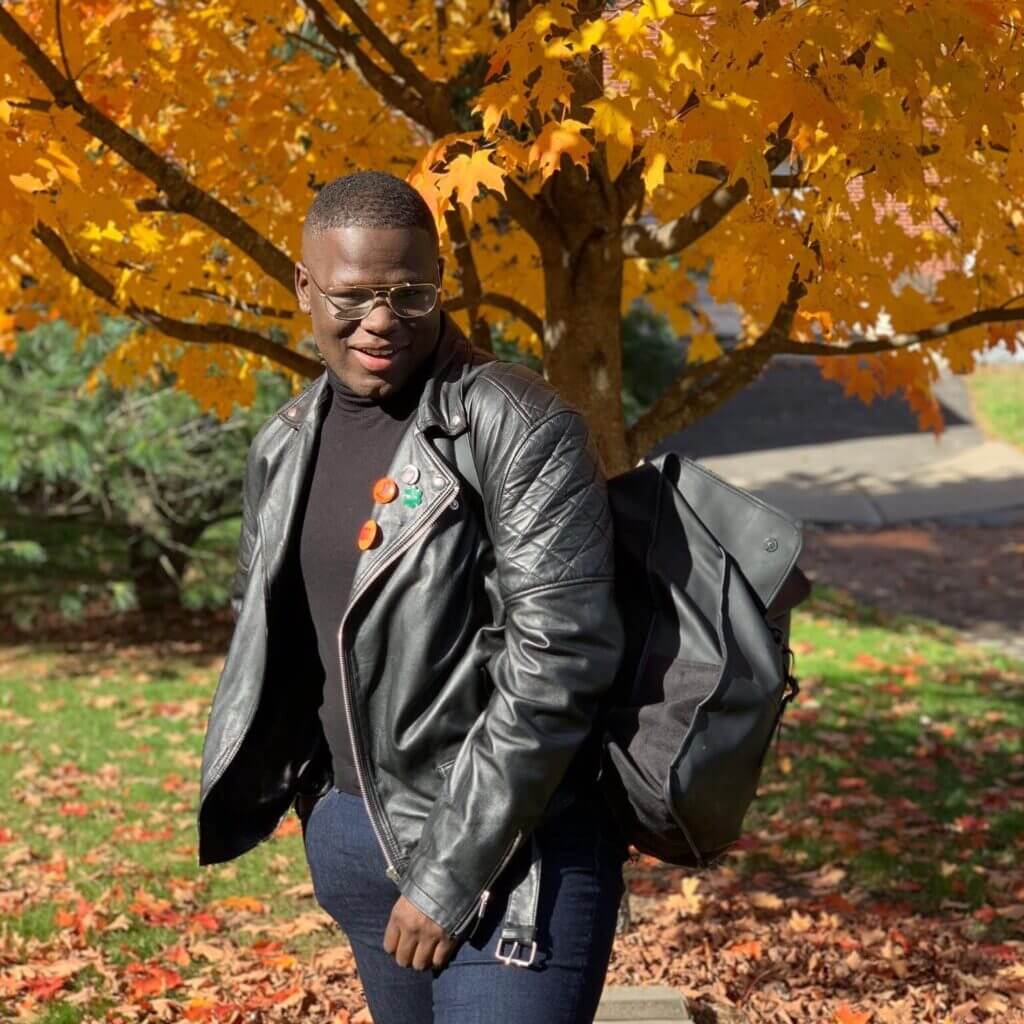 Lester Mayers stands in front of a tree with yellow, changing fall leaves.