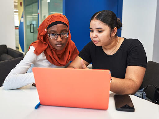 A Peer Leader helps a new graduate with college enrollment paperwork, one of the ways we help students beat summer melt. 