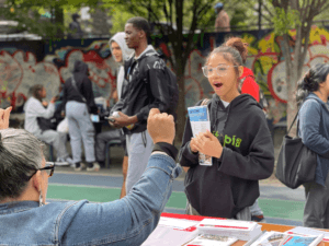 A college rep talks to a prospective student who has her look of surprise on her face. 