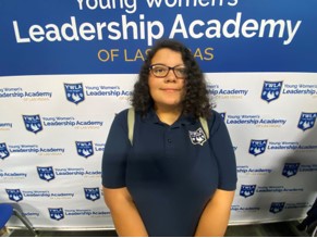 Melena from YWLA Las Vegas poses for a picture in front of a branded step and repeat banner.