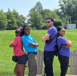 A director of college counseling and her students pose in front of a college campus lawn.