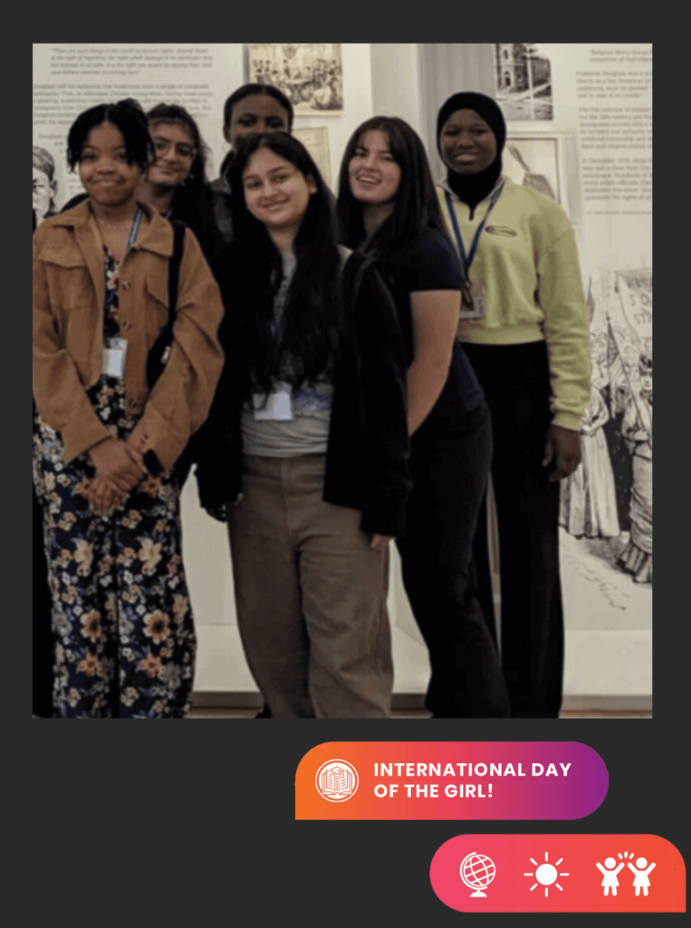 Group of girls at museum pose for photo for NYC Votes Youth Ambassadors program, with icons on lower right and text "International Day of the Girl"