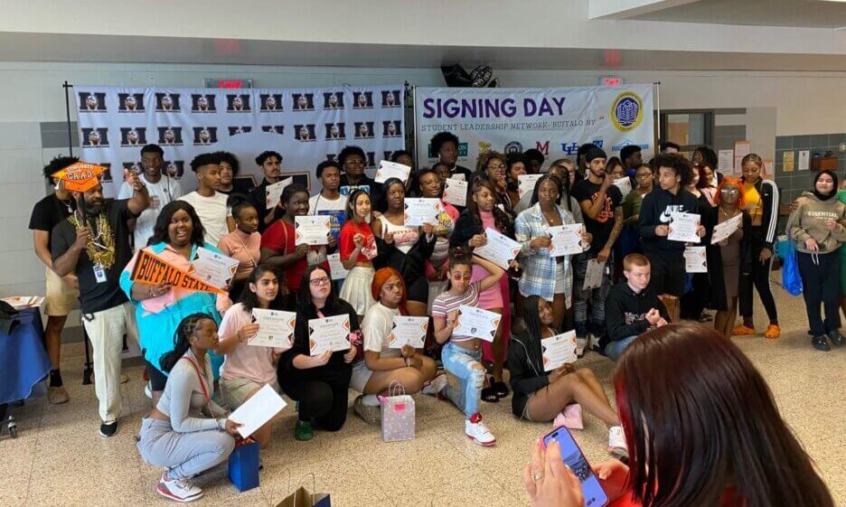 McKinley High School students hold up college pennants and acceptance letters on College Signing Day