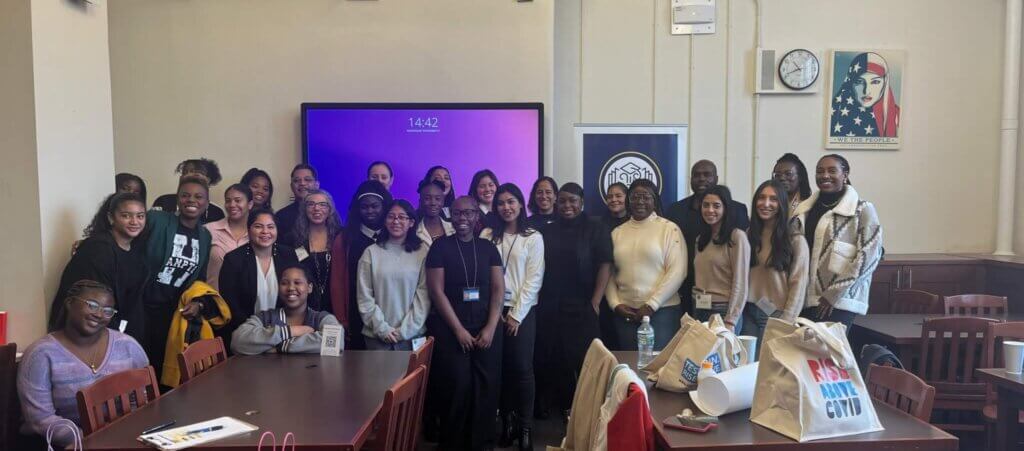 Nearly 30 adult volunteers and student ambassadors pose for photo in front of the classroom.