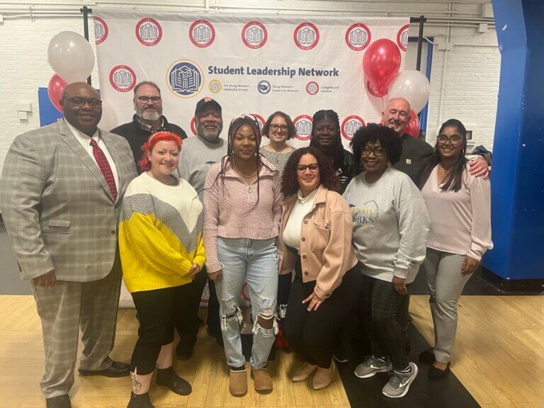 Group of college access professionals gather for photo in front of Student Leadership Network backdrop