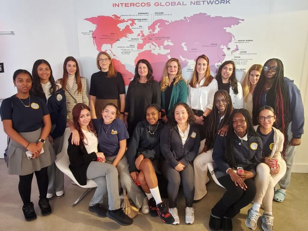Intercos staff and TYWLS students pose in front of a world map of Intercos offices and facilities.