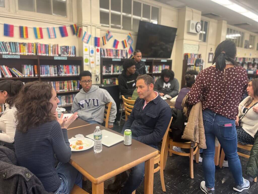 Alumni and high school teacher have lunch together in the library