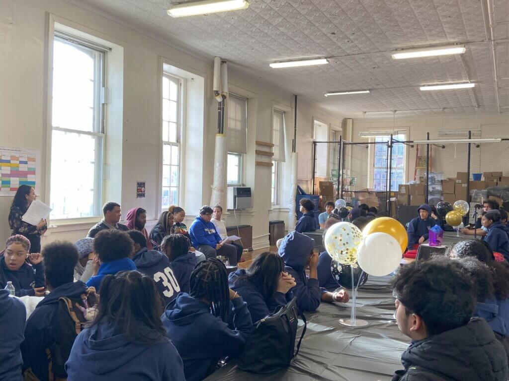 Alumni panel is seated on left by windows, with four long tables of students seated to the right