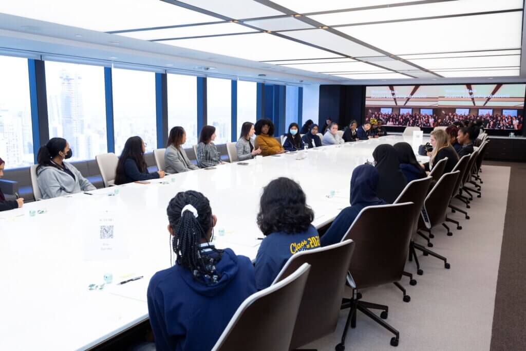 Students and Apollo employees are seated around a long conference table