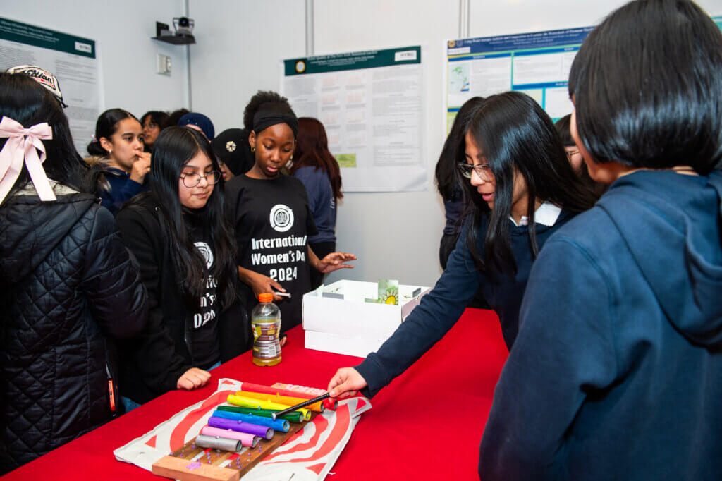 Student tests out a homemade xylophone while other students look on