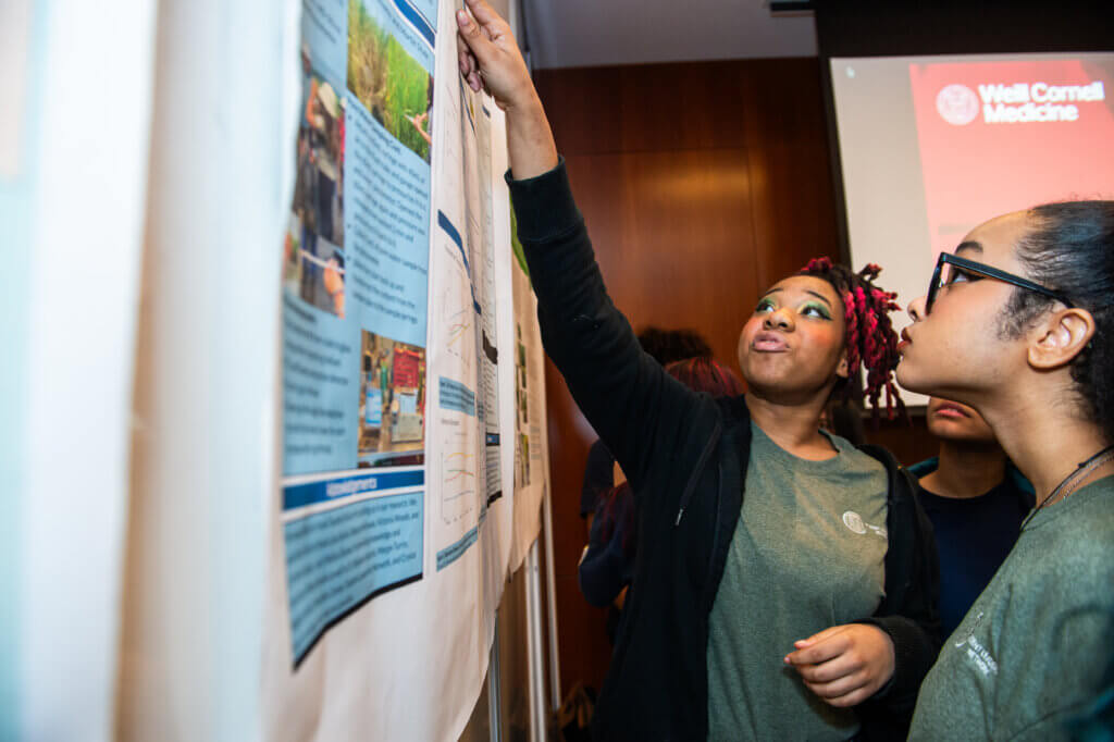 Student points to a research poster on the wall