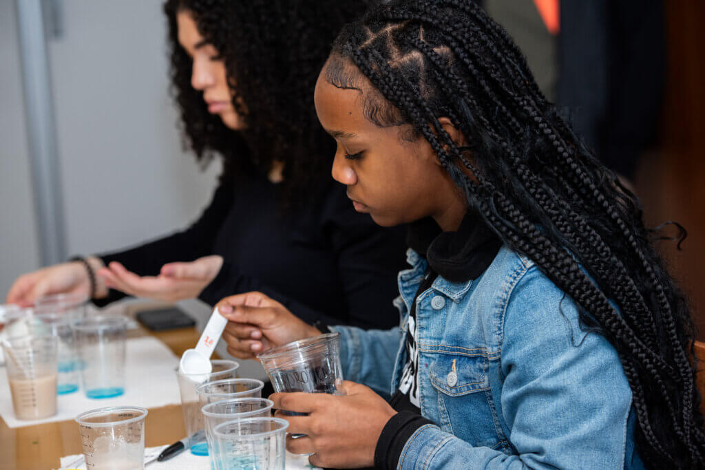 Two students measure out quantities of enzymes into plastic cups