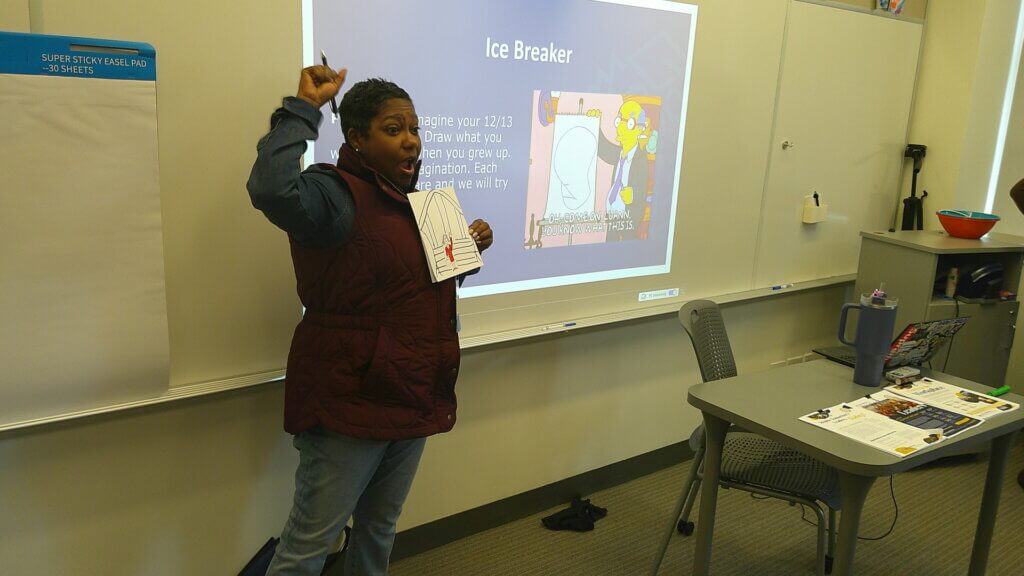 Educator shows her drawing and holds up a fist while explaining her artwork
