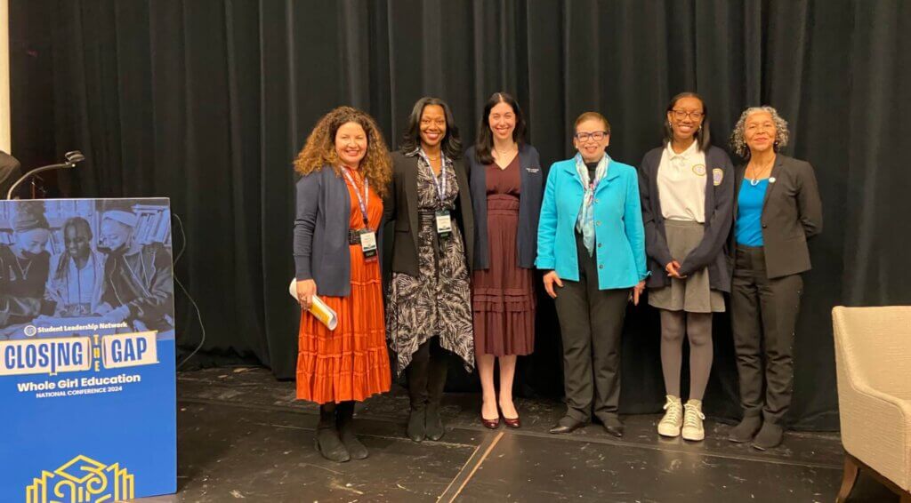 Speakers and event organizers gather on stage for photo