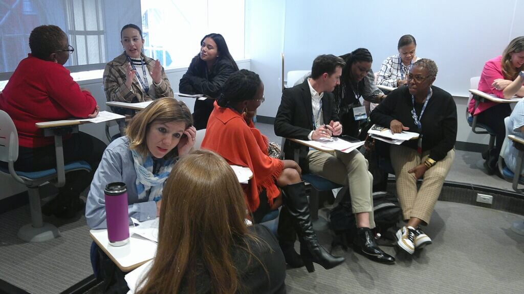 Educators seated in groups of two and three to discuss a workshop