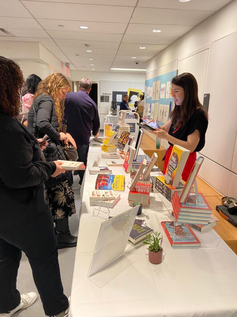 Table of books with adults browsing on one side