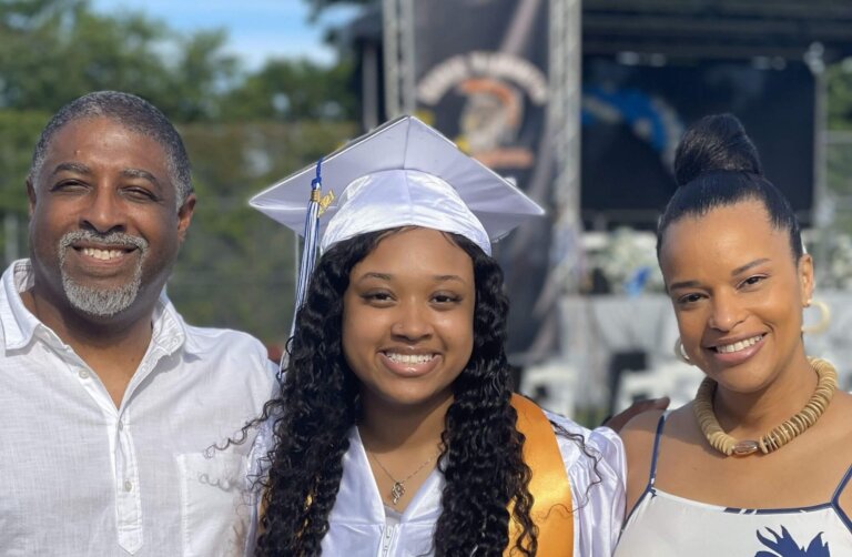Young woman in a graduation cap and gown with her parents on either side of her