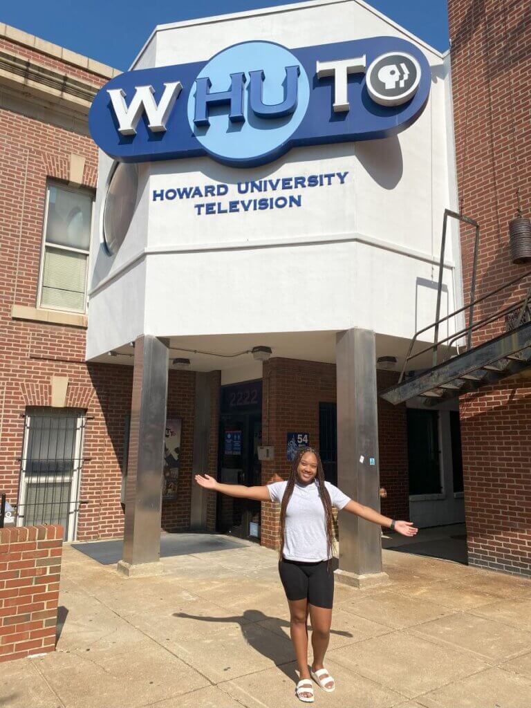 College student stands in front of Howard University TV studio building