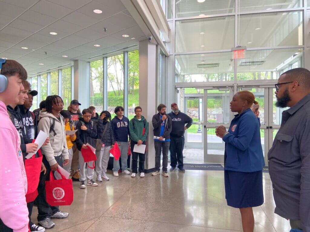 Two staff members welcome students in a sunny atrium