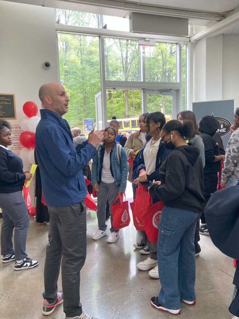 A staff member welcomes a group of students in a sunny room