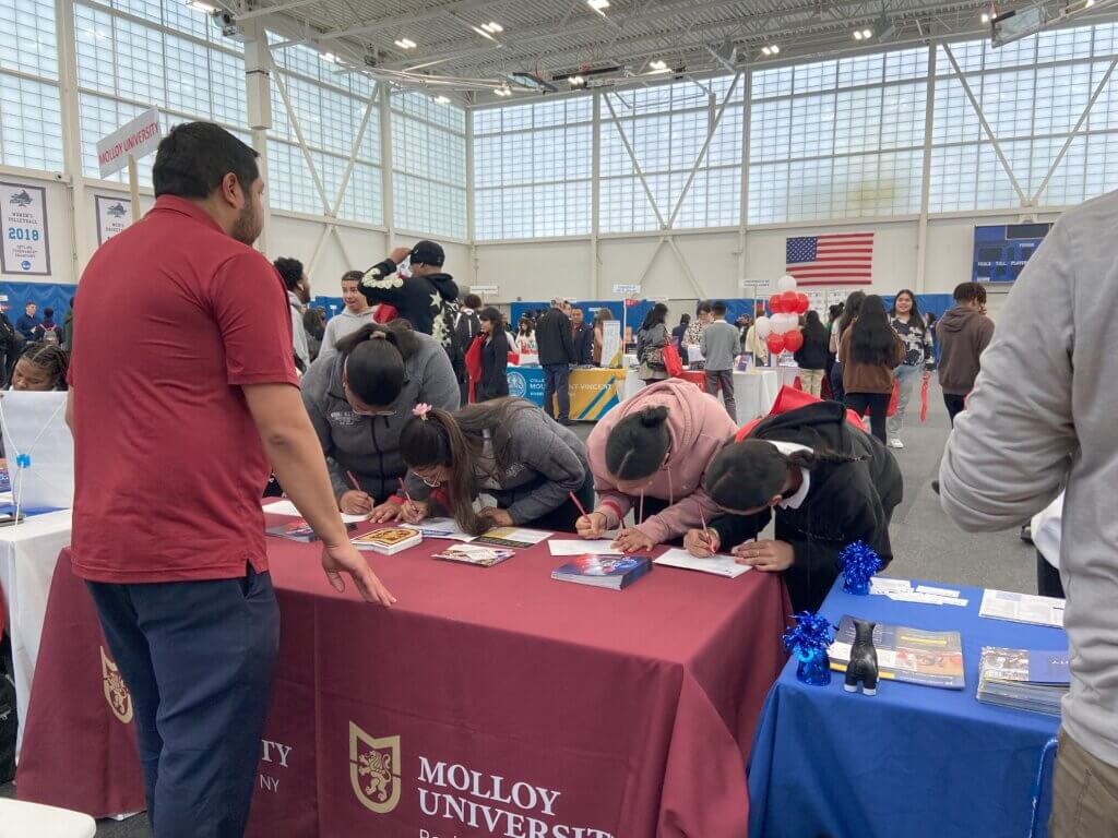 High school students sign up for more information at the postcards on Molloy University's college table