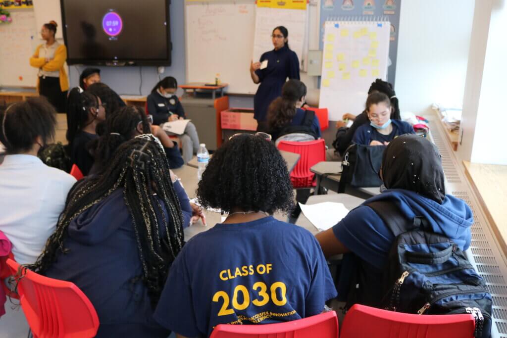 Three female students sit with back to camera with "Class of 2030" on the back of one student's shirt