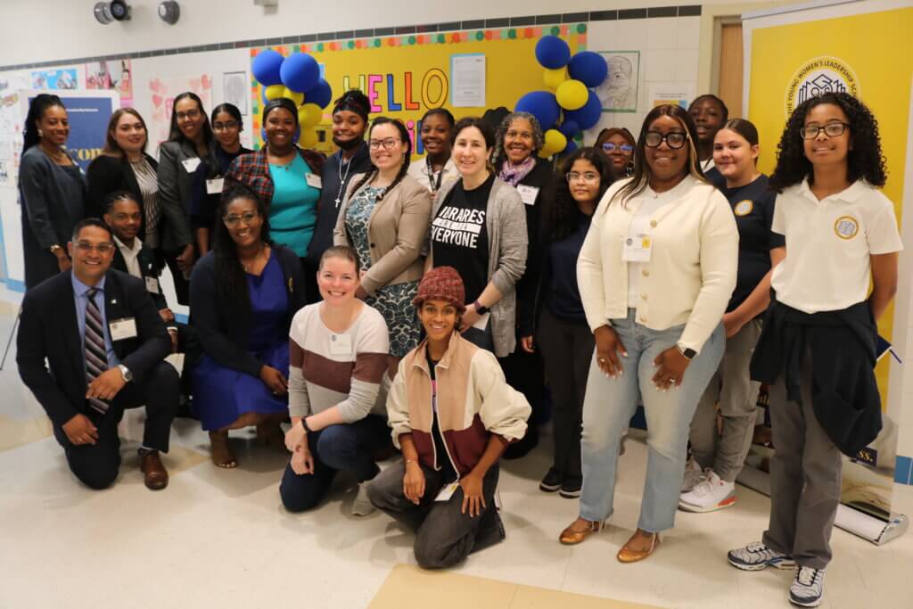 Group of volunteers and students take photo in front of bulletin board