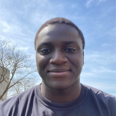 Young man wearing blue shirt looks to camera with blue sky in background