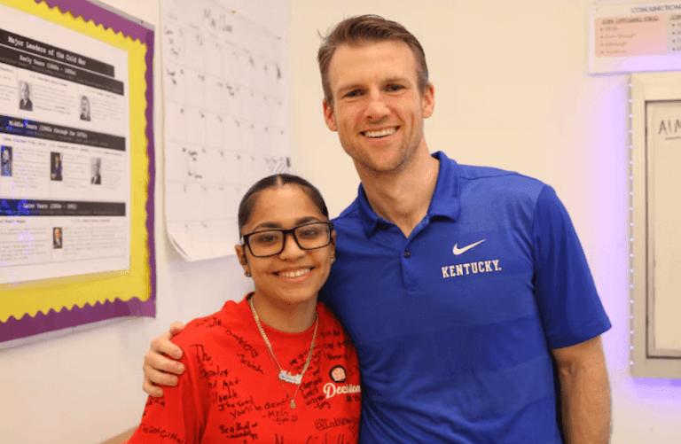 Student wears her red "I Decided" college t-shirt, standing next to her history teacher