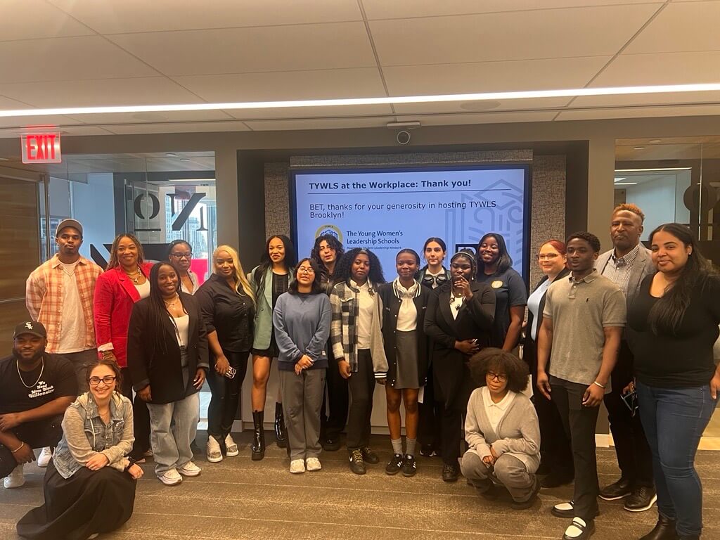 Students and BET employees pose for group photo in front of a screen that says "TYWLS at the Workplace Thank You!"