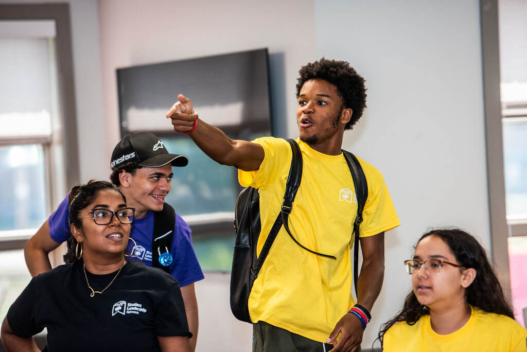 Student holds up arm to point to something on his right