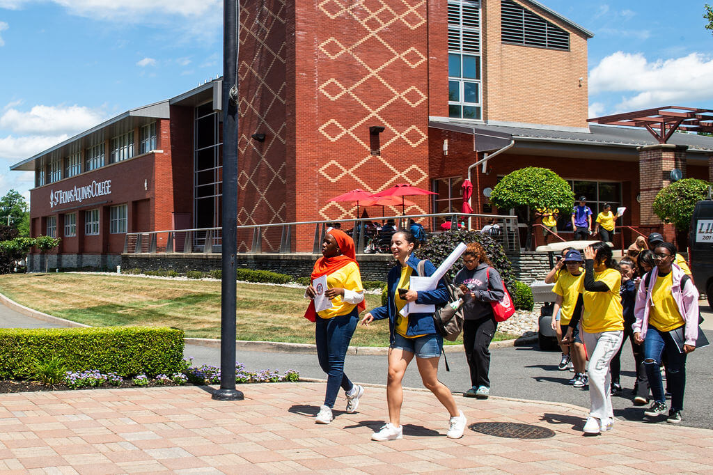 Students and staff walk across a college campus