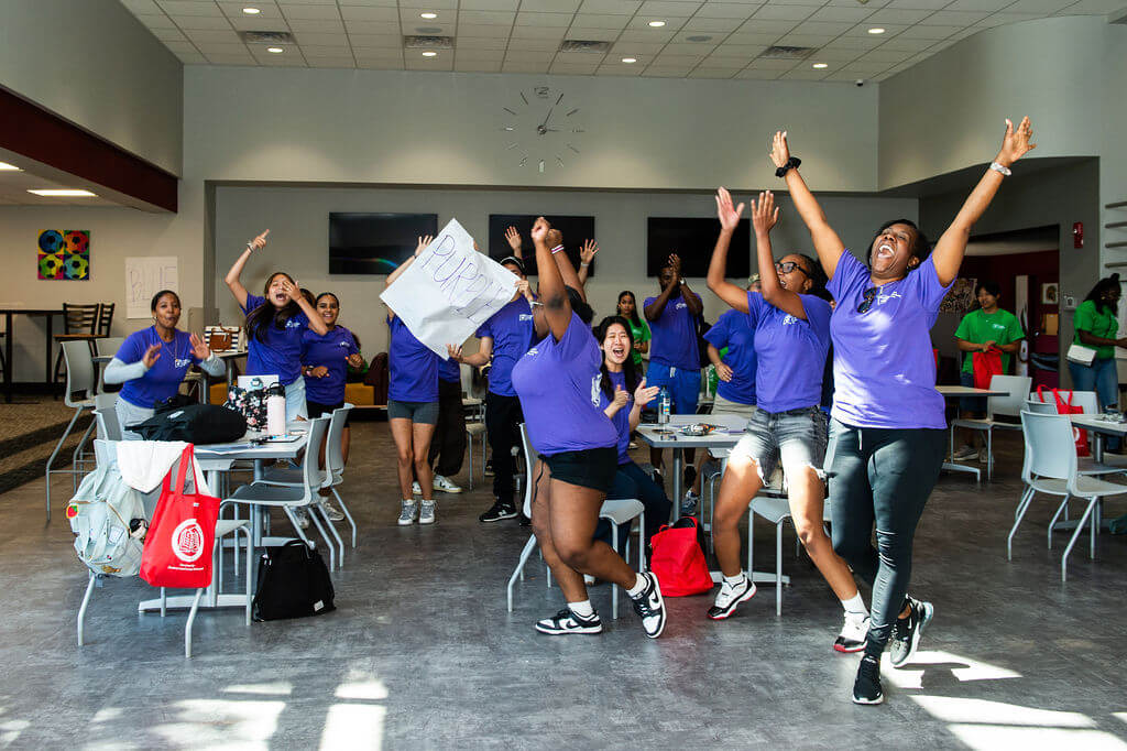 Students and staff in purple t-shirts jump for joy