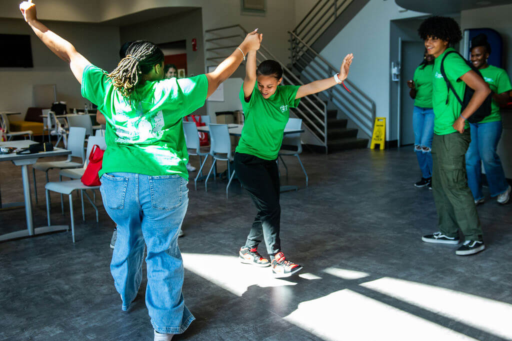 Students in green shirts perform a dance