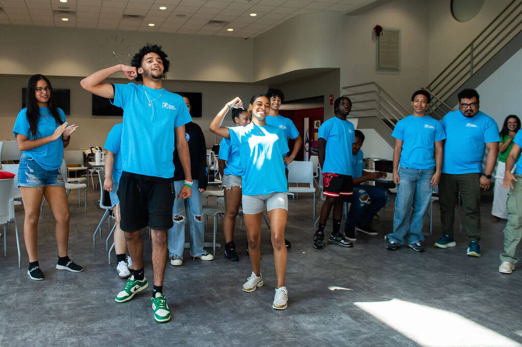 Students in blue shirts perform a dance