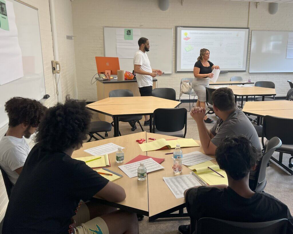 Two counselors lead a workshop in front of classroom with students seated in foreground