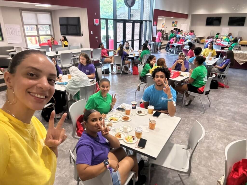 A counselor and students pose for a selfie in the cafeteria, their hands making a peace sign