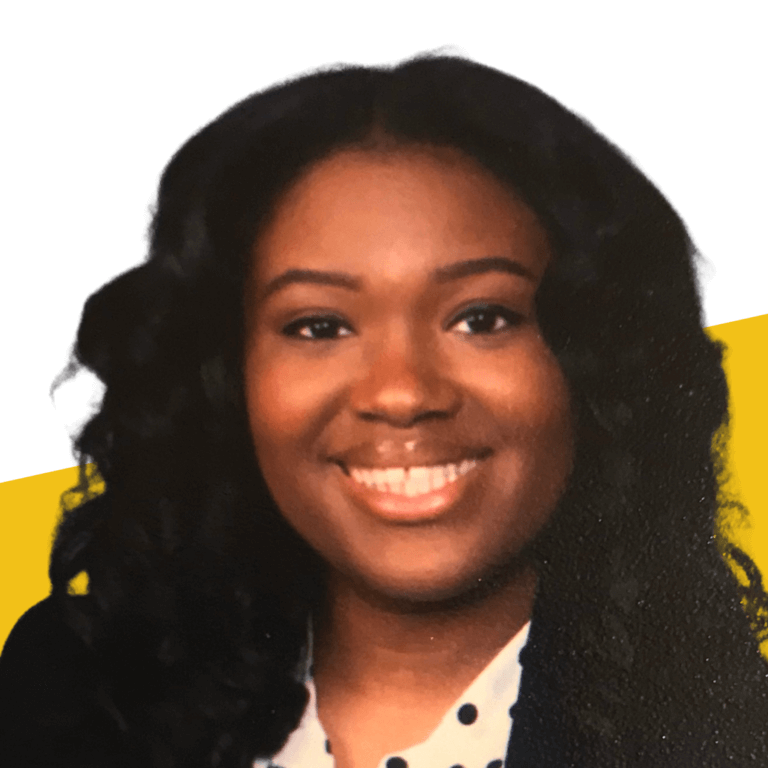 staff headshot of woman with wavy black hair, wearing a white and black polka dotted shirt and dark blazer