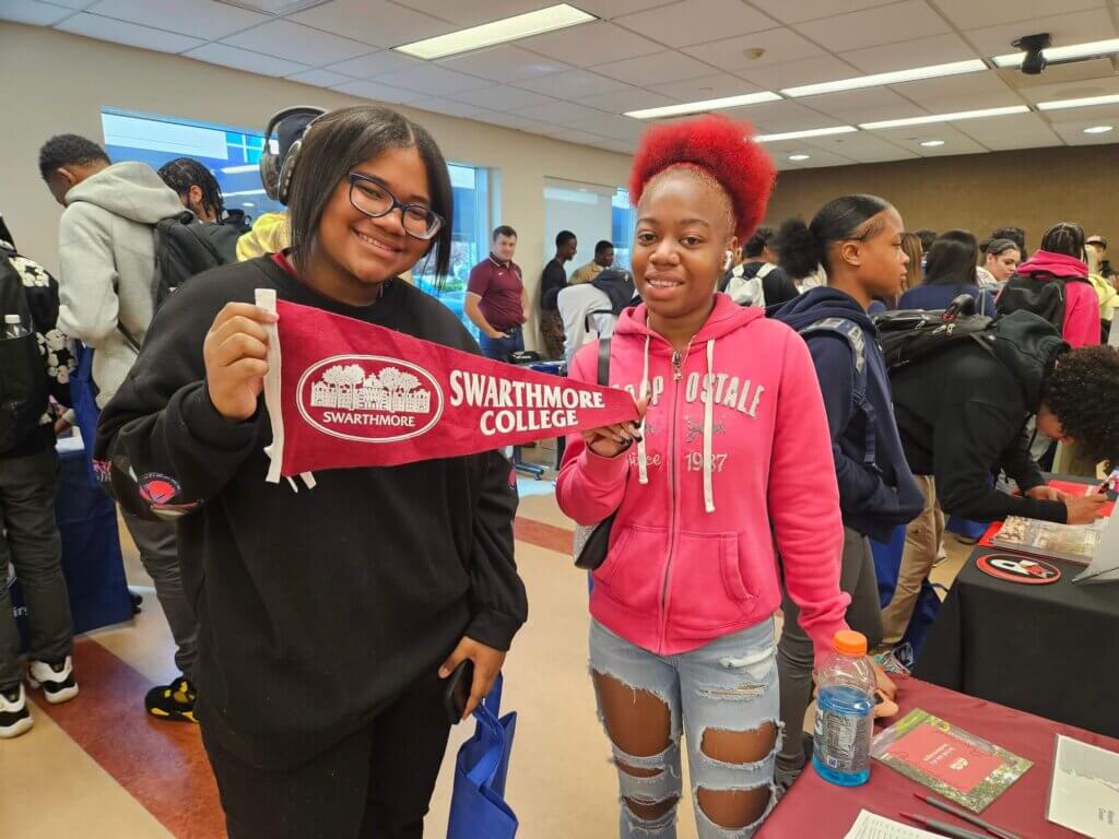 Two female students hold up a Swarthmore College pennant