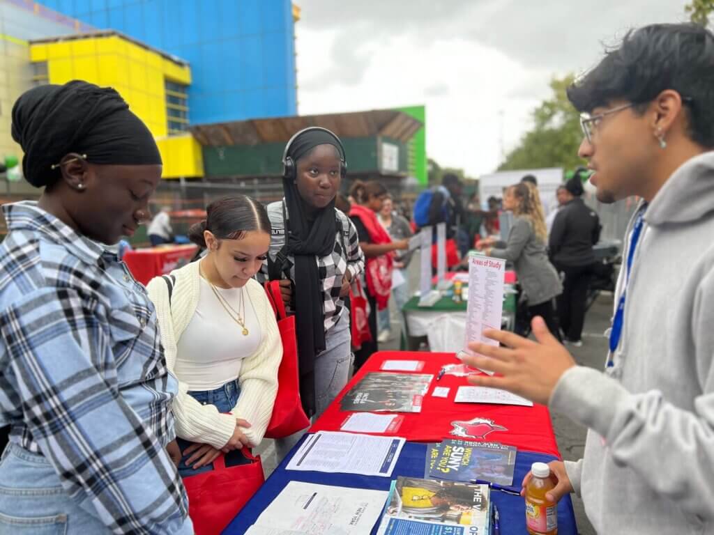 Three young women talk to a college rep at the SUNY table