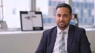 A 2024 Honoree, Angel Santana, sits in an office with large windows and framed documents in the background.